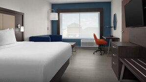 A hotel room with a bed, desk, chair, TV, and a large window.