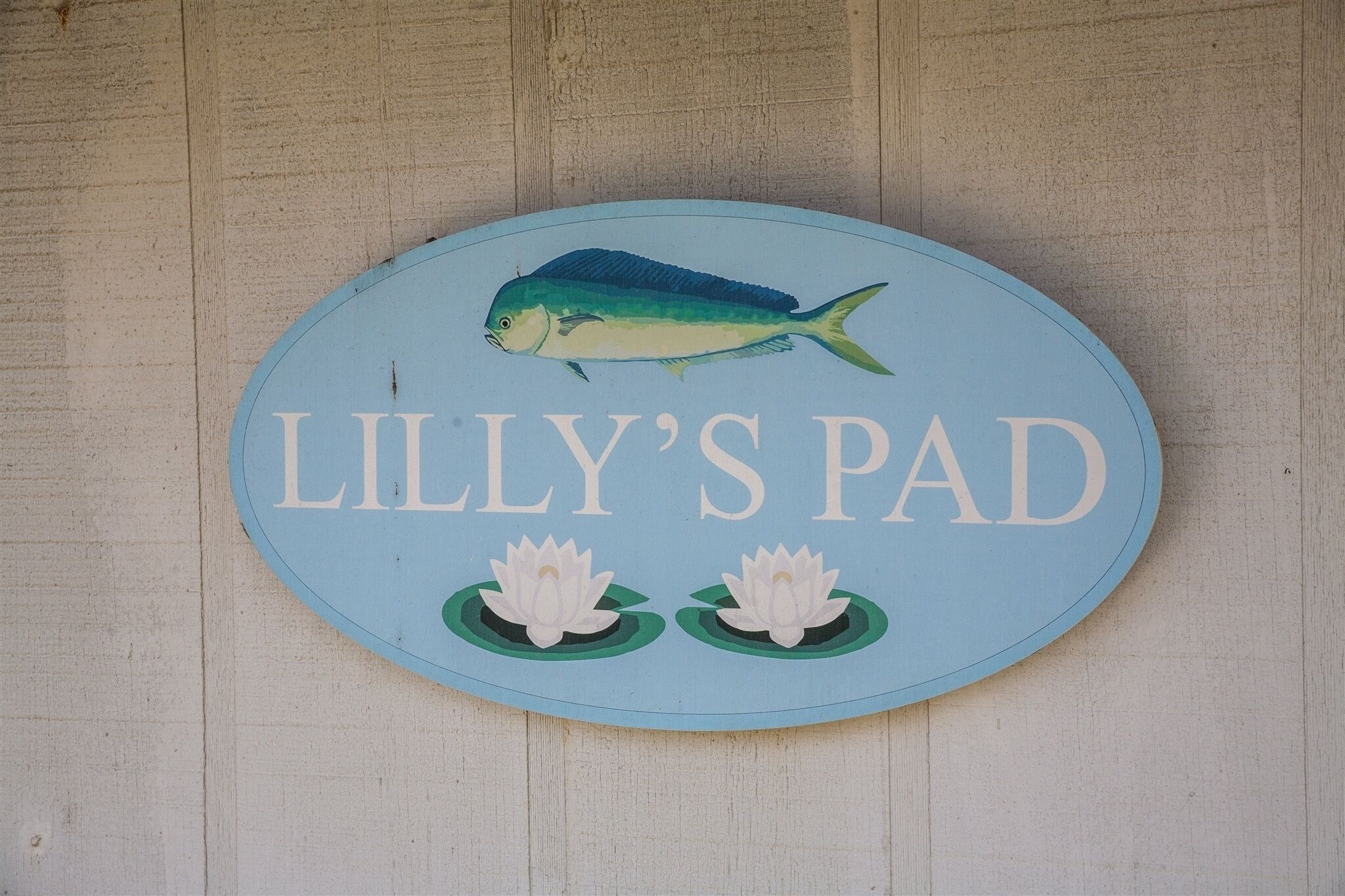 A sign with a fish and lotus flowers, labeled "LILLY'S PAD".