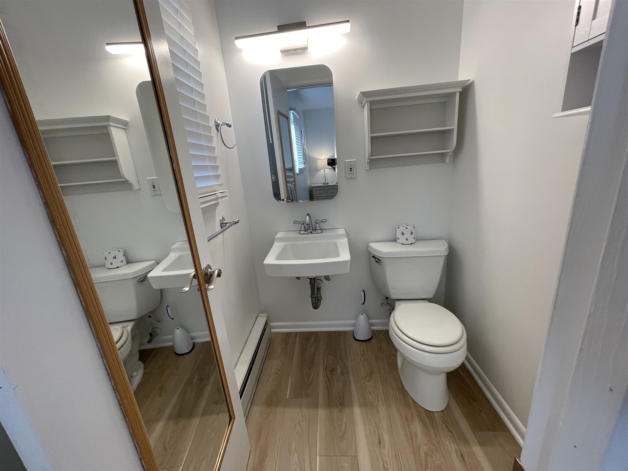 A compact bathroom with a toilet, sink, and mirror.
