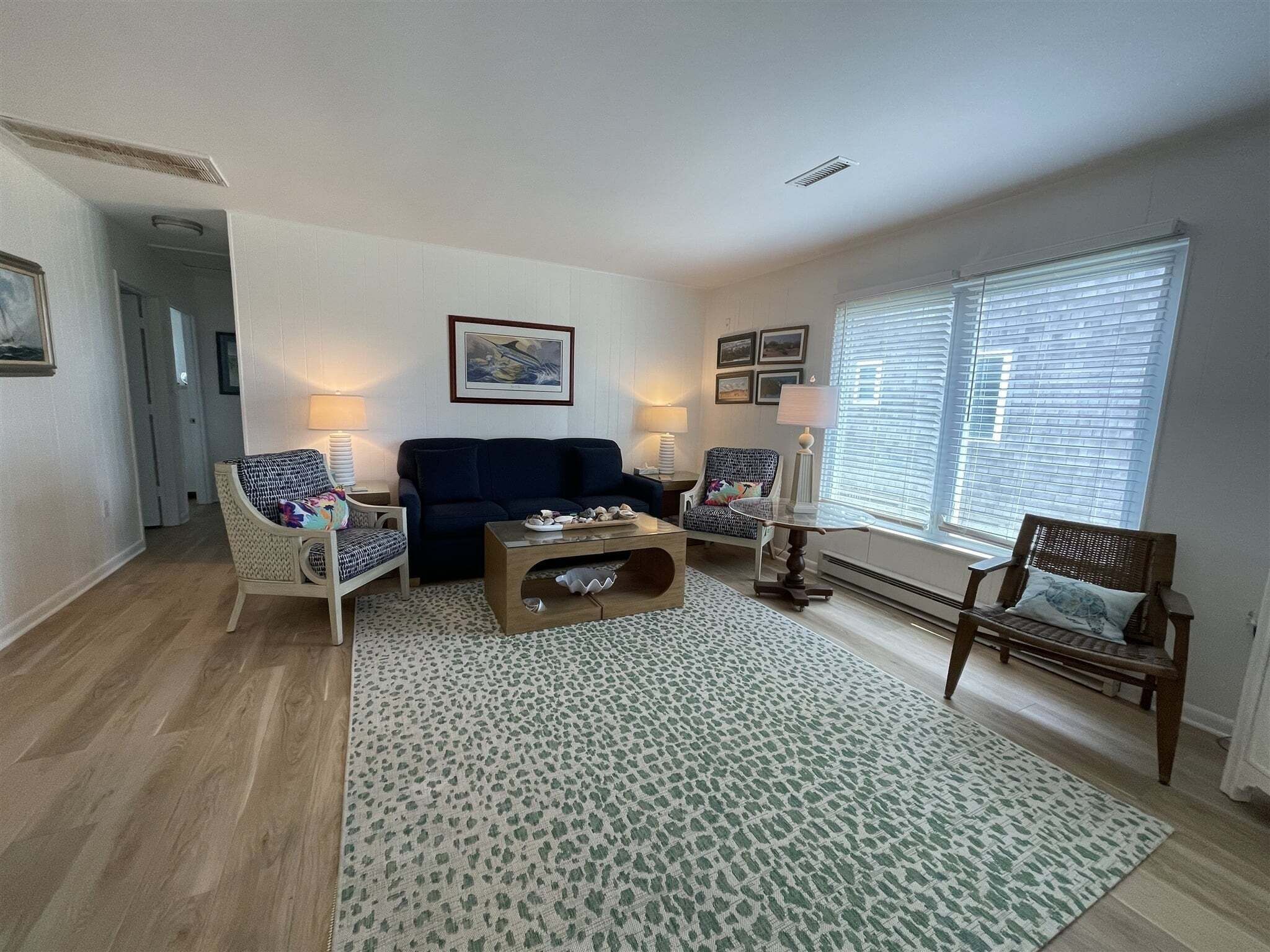 Un salon avec un canapé bleu foncé, deux fauteuils, une table basse et un tapis à motifs.