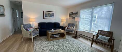 Un salon avec un canapé bleu foncé, deux fauteuils, une table basse et un tapis à motifs.