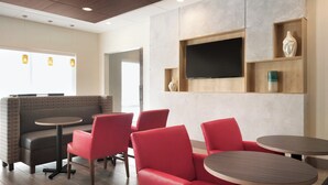 A modern interior with seating arrangements, a flat-screen TV, and a wooden shelf with decorative items. - Holiday Inn Express & Suites-Cincinnati South - Wilder by IHG (Newport)