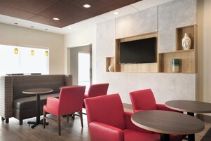 A modern interior with seating arrangements, a flat-screen TV, and a wooden shelf with decorative items.
