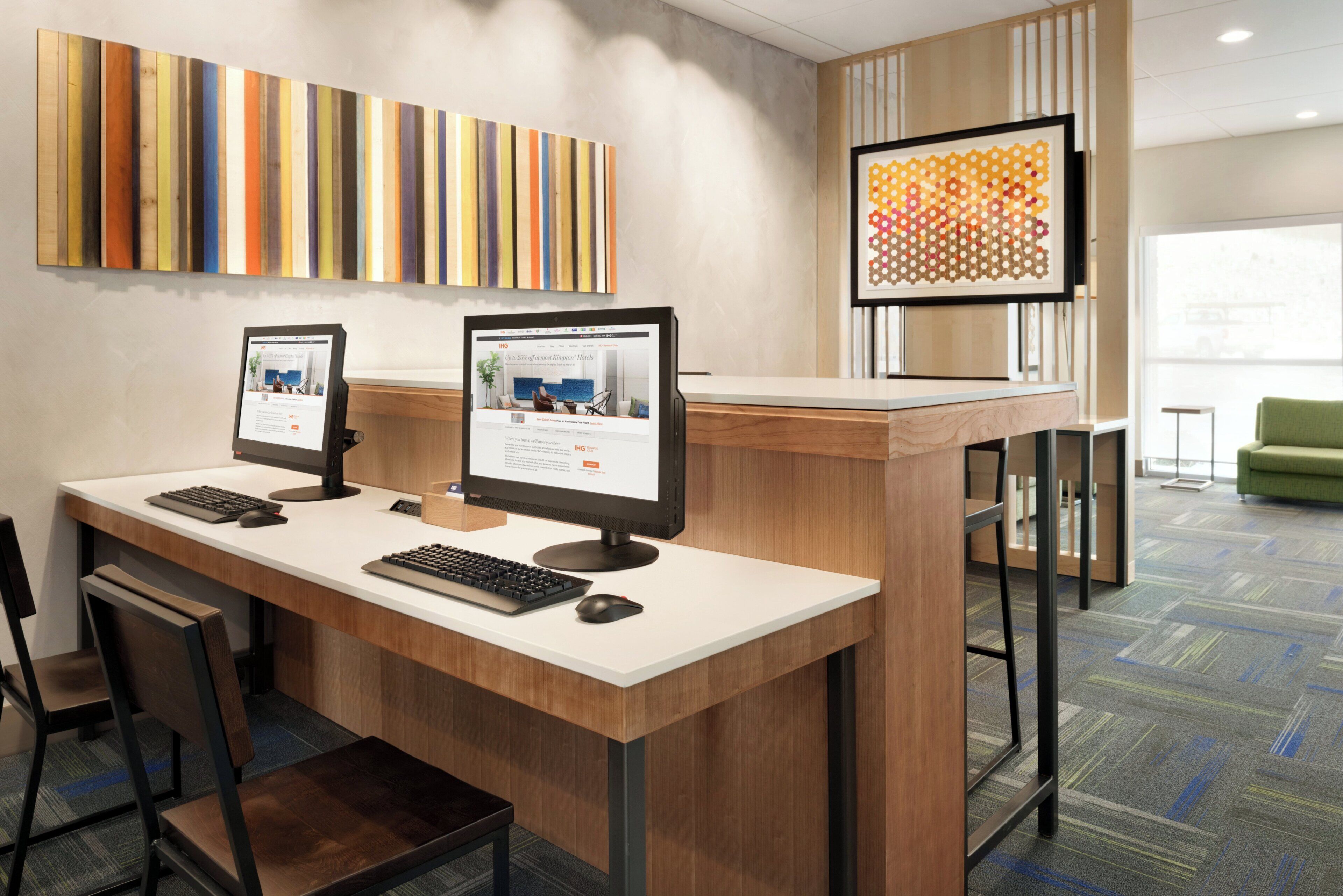 A reception desk with two computer monitors, a keyboard, and a mouse. There are chairs and a green sofa in the background.