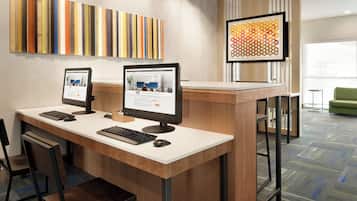 A reception desk with two computer monitors, a keyboard, and a mouse. There are chairs and a green sofa in the background.