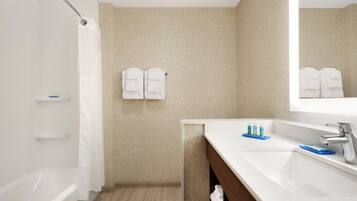 A bathroom with a shower, a sink, and a mirror.