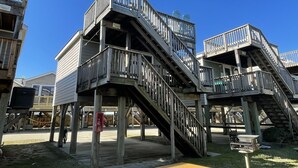 A multi-level wooden structure with balconies, staircases, and a barbecue grill.