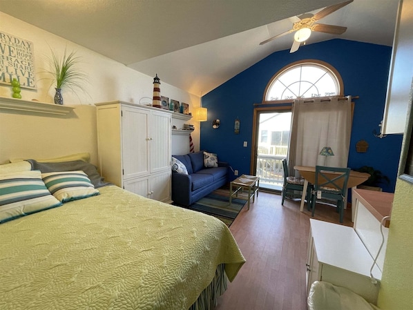 A cozy room with a bed, a blue sofa, a small table, and a window with a view.