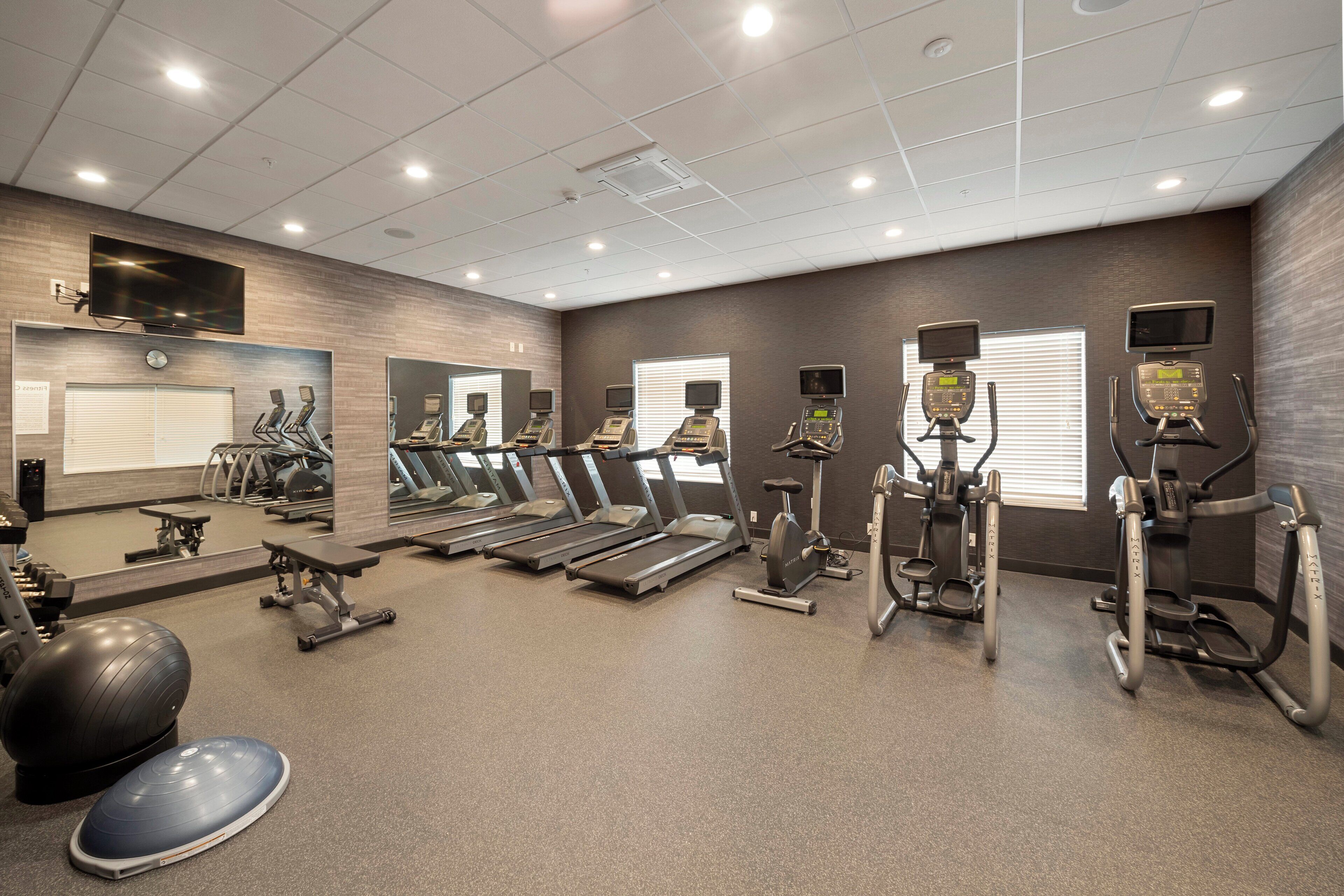 A gym with treadmills, elliptical machines, and weight equipment.