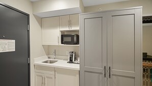 A compact kitchen with a microwave, coffee maker, and a sink.