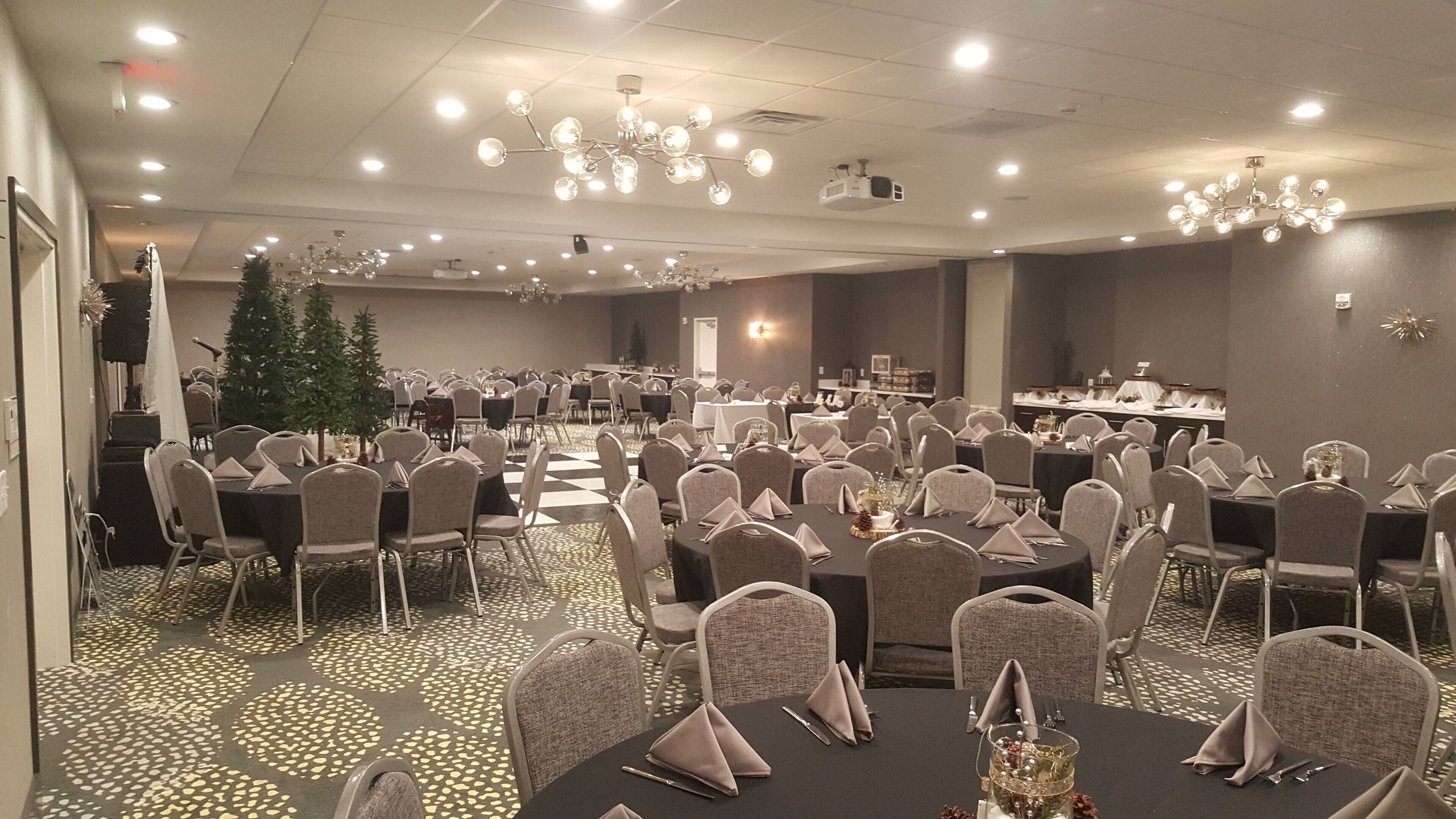 A banquet hall with round tables, chairs, and a Christmas tree.