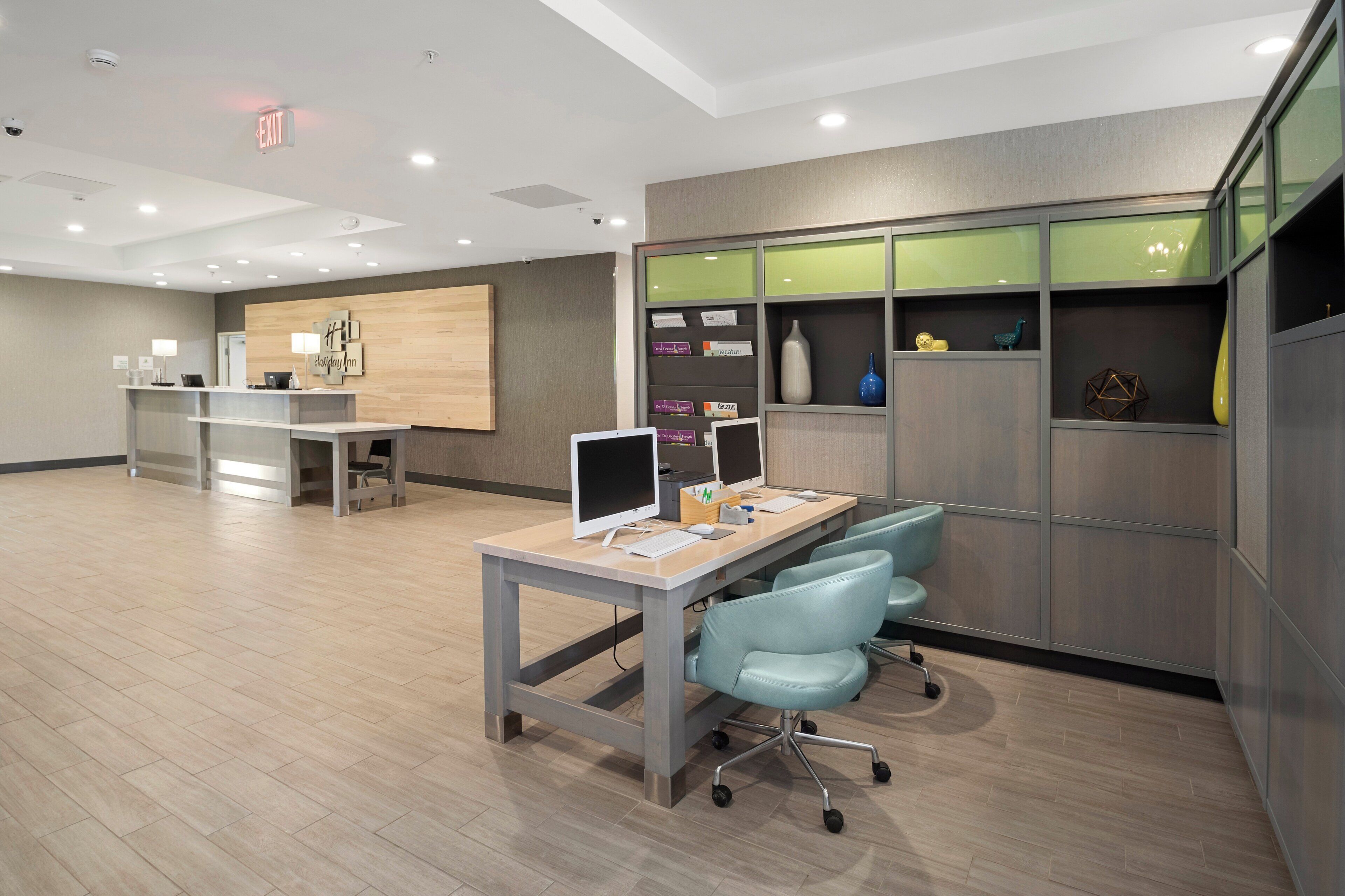 A hotel reception area with a desk, computer, and seating.