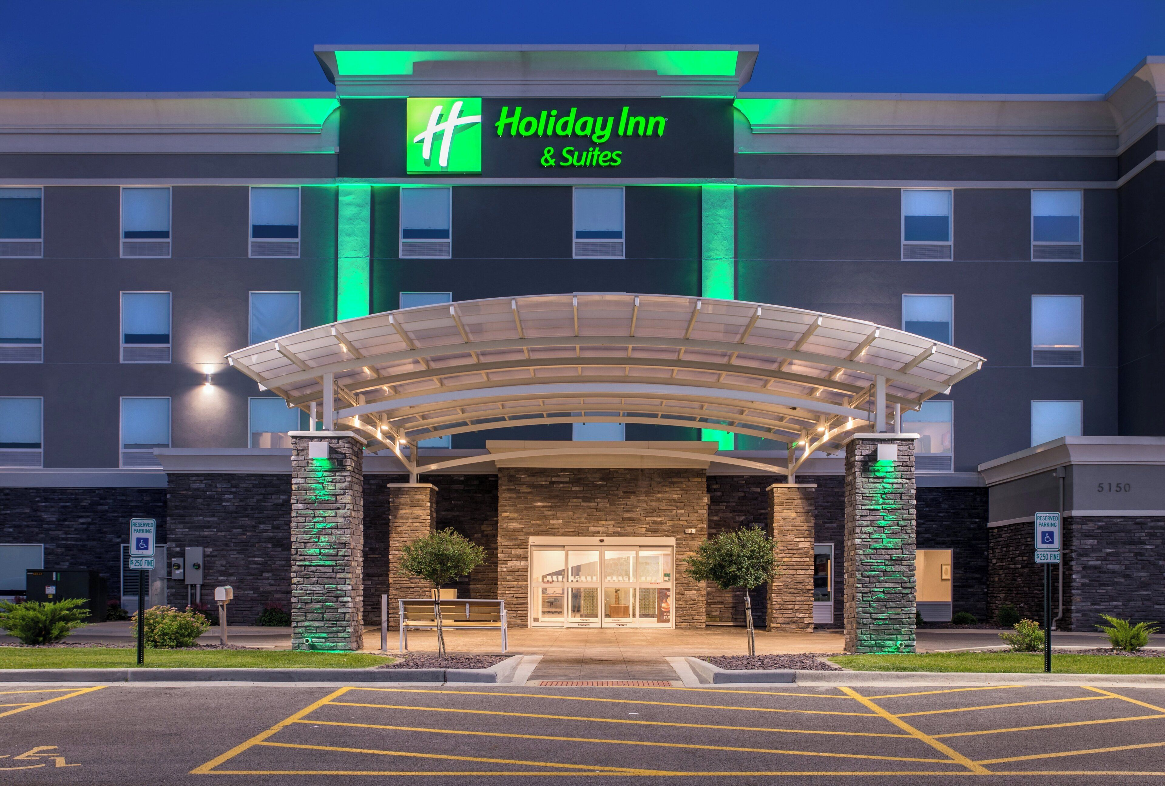 A Holiday Inn & Suites hotel entrance with a covered driveway and stone pillars.