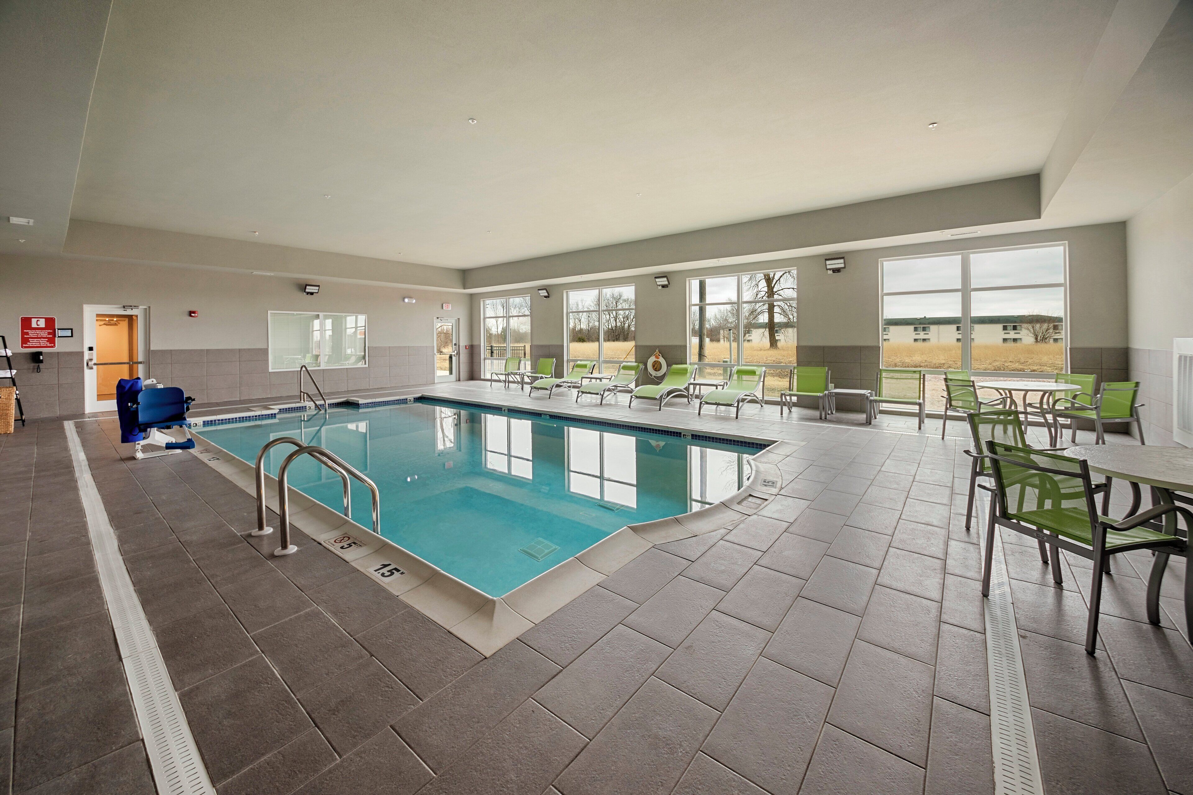 An indoor swimming pool with clear lanes, a changing room, and a seating area with tables and chairs.