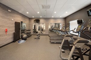 A gym with treadmills, elliptical machines, and free weights.