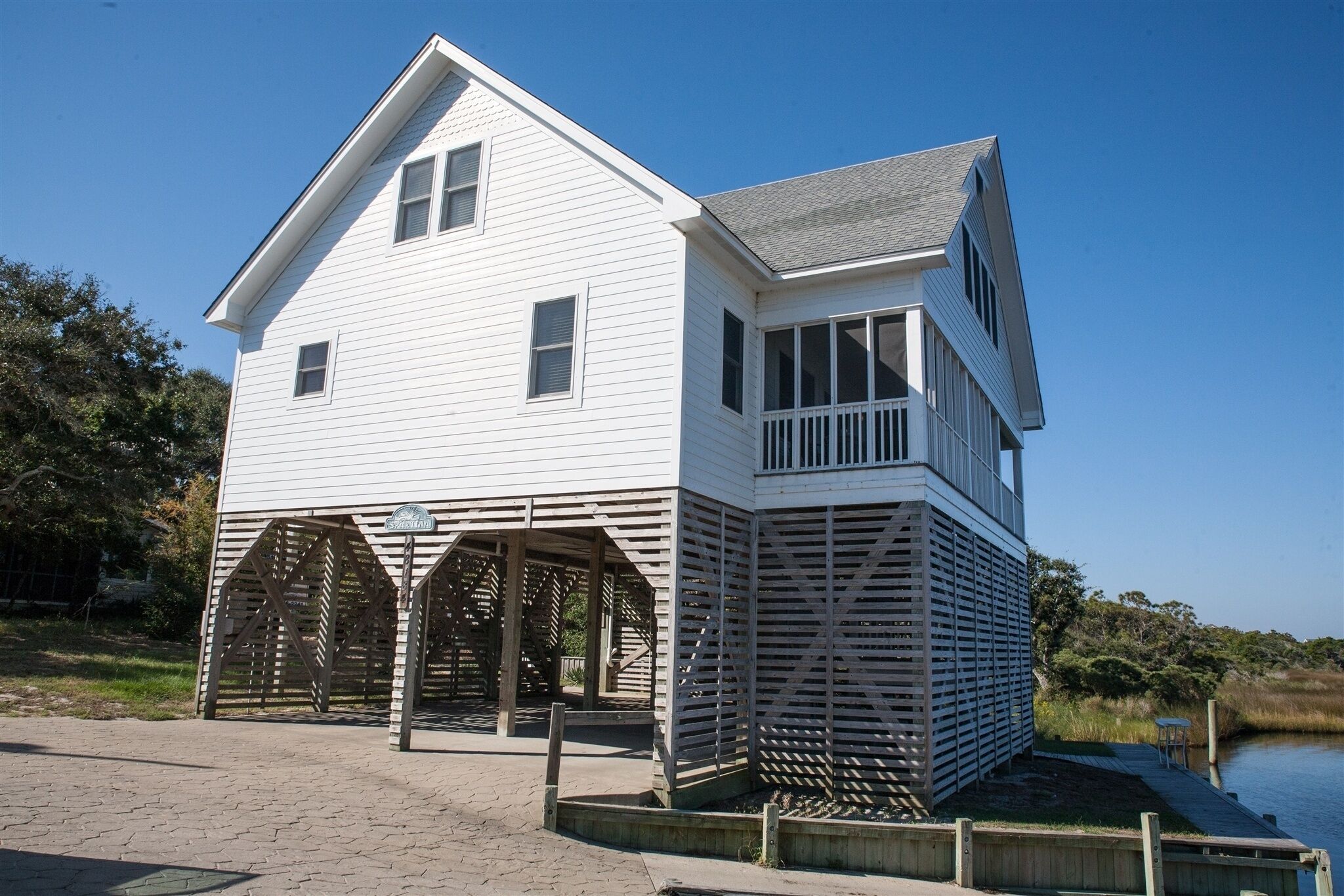 A white two-story house with a covered porch and a small deck.