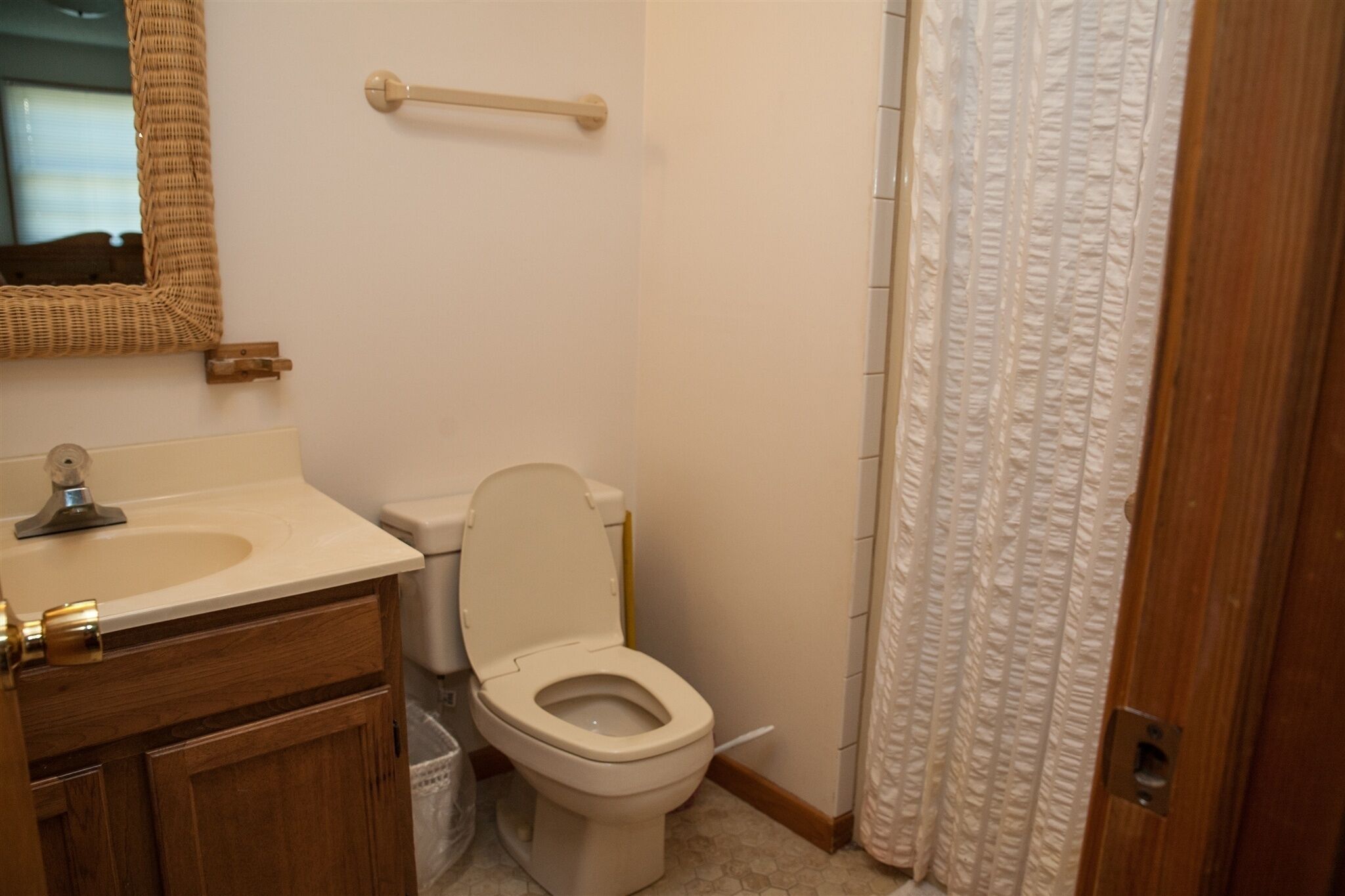 A bathroom with a toilet, sink, and mirror.