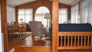 A cozy room with a wooden floor, a dining table with chairs, a sofa, and a lamp. - Chez-toni 3 Bedroom Cottage by RedAwning (Avon)