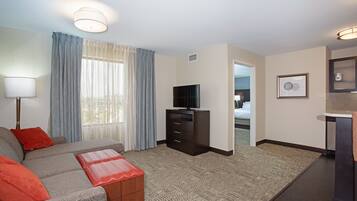 A hotel room with a sofa, a TV, a small cabinet, and a bathroom visible through an open door.