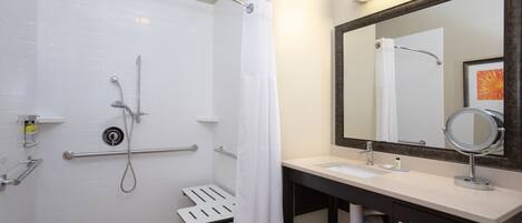 A bathroom with a shower, a sink, a mirror, and a towel rack.