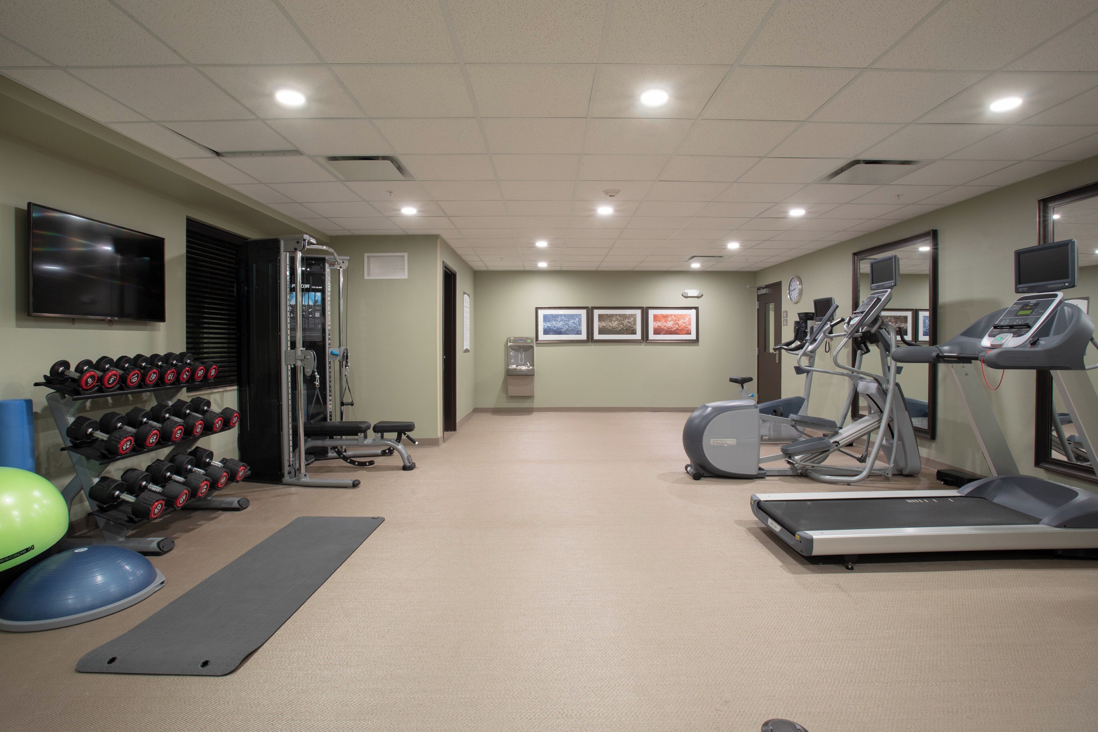 A gym with exercise equipment, a television, and a water dispenser.