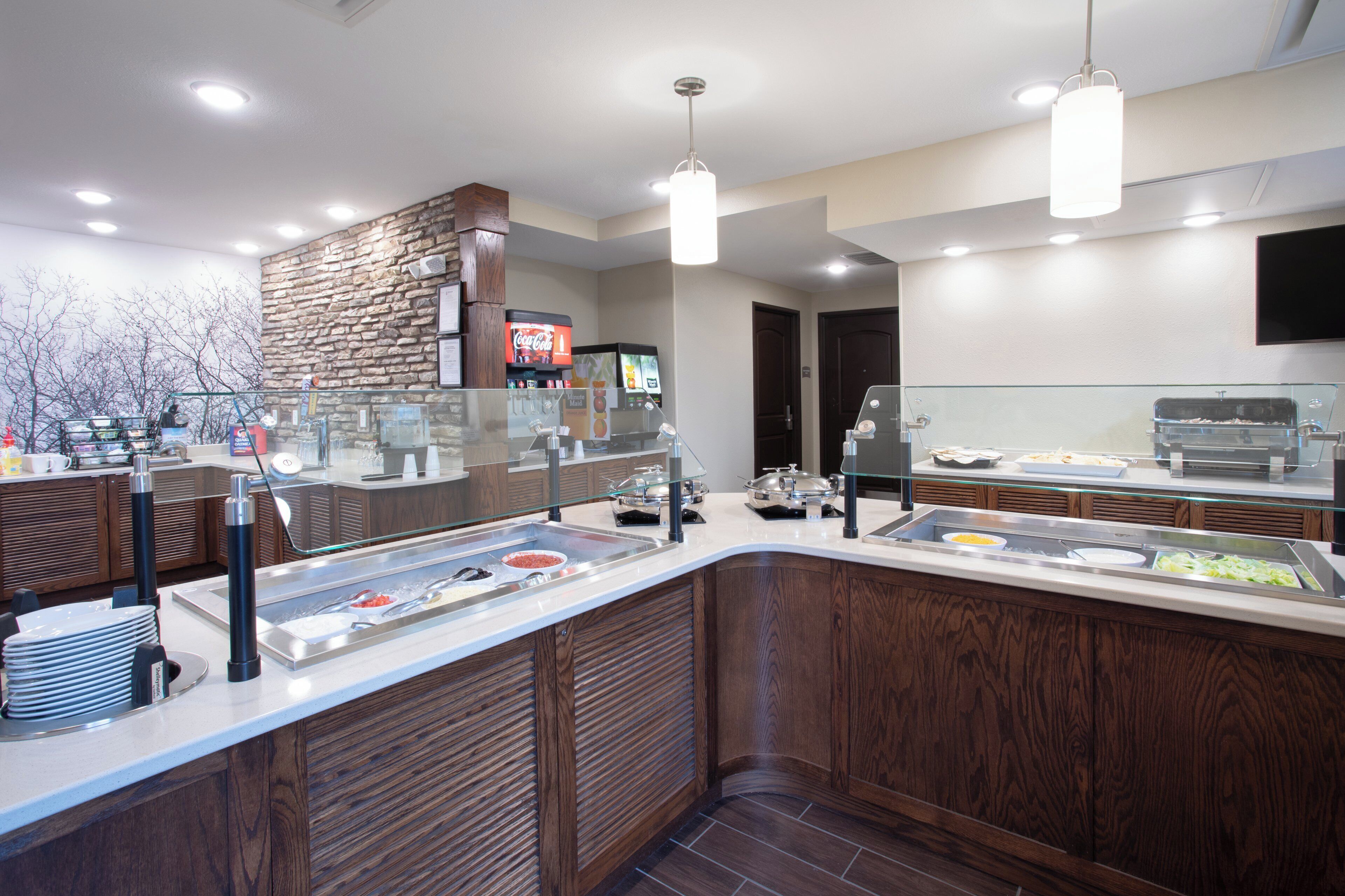 Un espace buffet proposant une variété de plats, un réfrigérateur rempli de Coca-Cola et une vitrine réfrigérée.