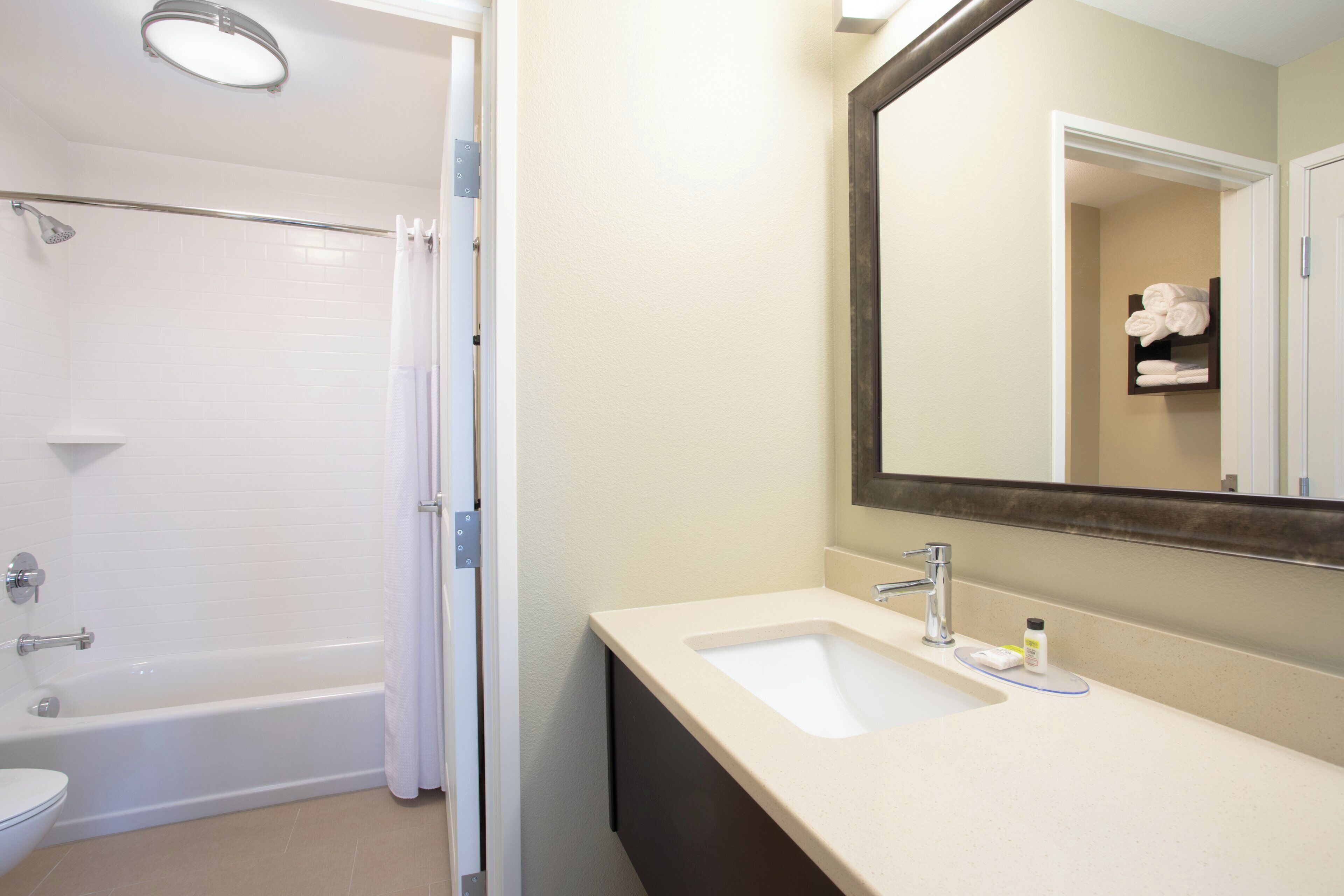 A bathroom with a bathtub, a shower, a sink, and a mirror.