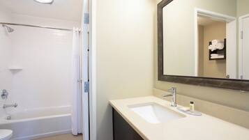 A bathroom with a bathtub, a shower, a sink, and a mirror.