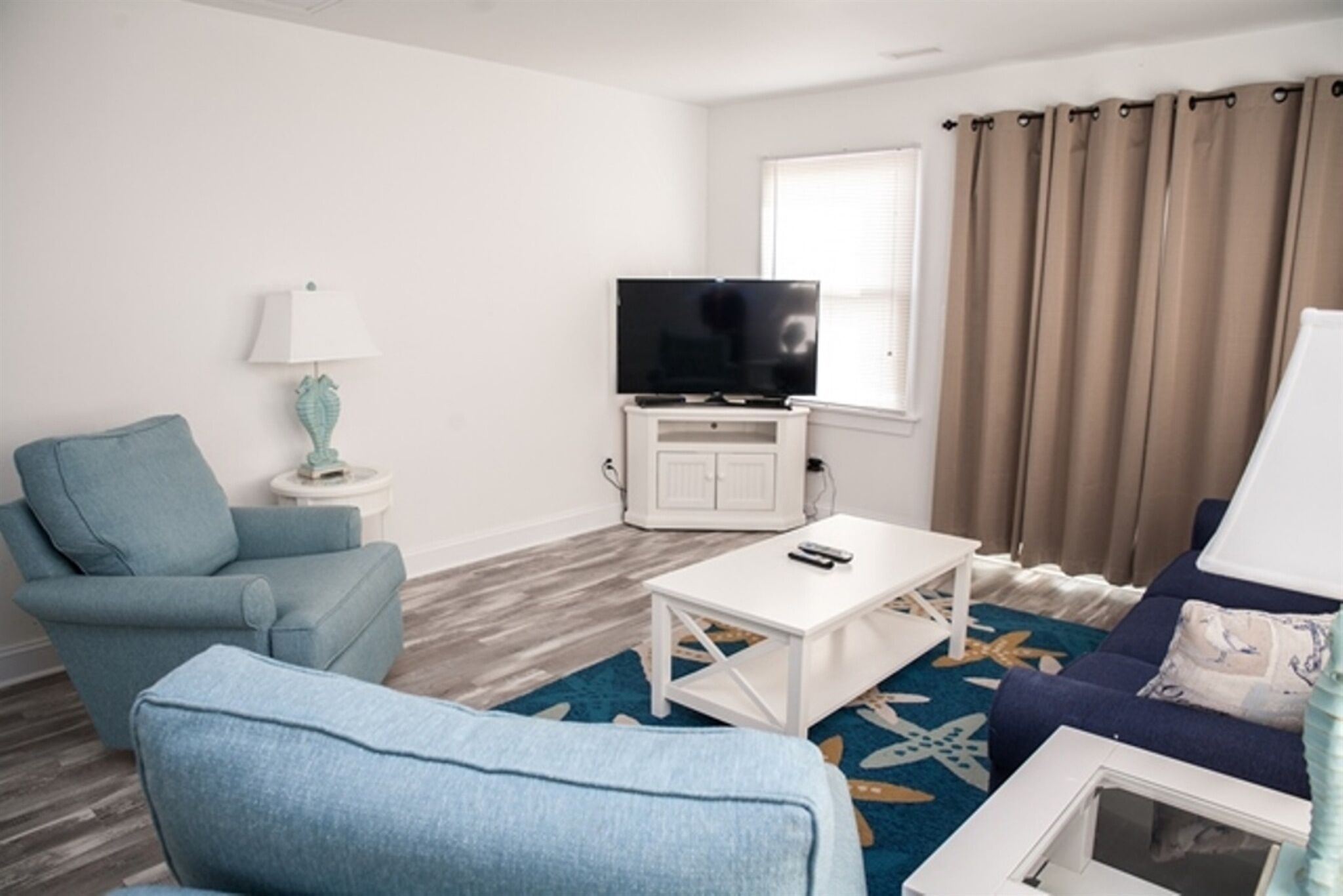 A living room with a sofa, armchair, TV, and a small table.