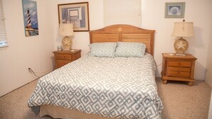 A bedroom with a wooden bed, two nightstands, a window with blinds, and wall art.
