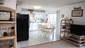 A compact living space with a kitchen, dining area, and a TV on a wooden stand.