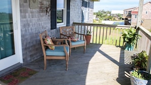 A wooden deck with two wooden chairs and a potted plant. - Austin's Pointe 4 Bedroom Cottage by RedAwning (Hatteras)