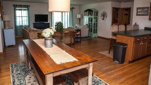A spacious living room with a wooden dining table, a sofa, and a TV in the background. - Austin's Pointe 4 Bedroom Cottage by RedAwning (Hatteras)