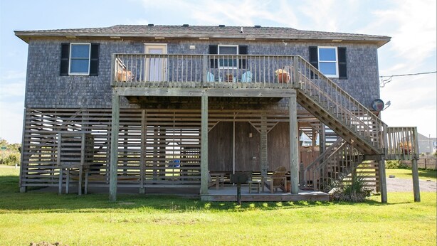 A two-story house with a wooden deck and a covered porch. - Austin's Pointe 4 Bedroom Cottage by RedAwning (Hatteras)