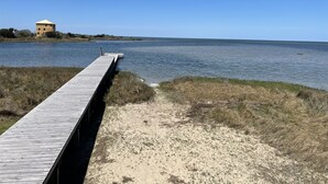 A wooden pier extending into a calm body of water, with a small building on the opposite shore.