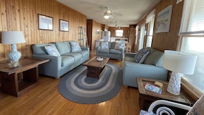 A cozy living room with wooden walls, two sofas, a coffee table, and a rug. - Time / Tide 4 Bedroom Cottage by RedAwning (Hatteras)