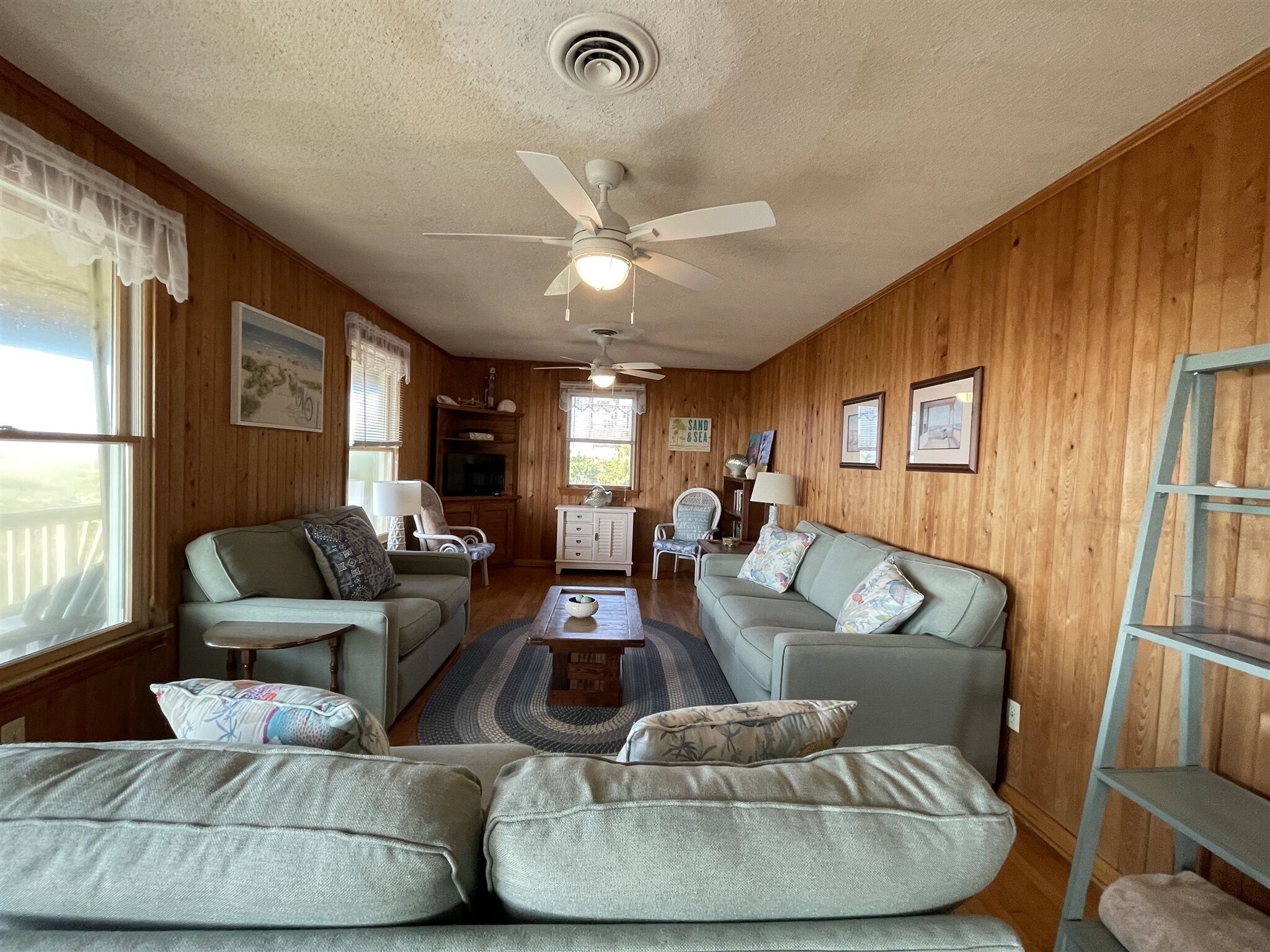 A cozy living room with two couches, a coffee table, and a ceiling fan.