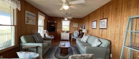 A cozy living room with two couches, a coffee table, and a ceiling fan.
