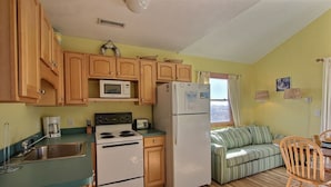 A compact kitchen with wooden cabinets, a microwave, a refrigerator, and a stove. - 40 Hatteras Blew Studio Bedroom Condo by RedAwning (Hatteras)