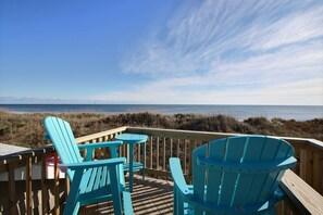 A wooden deck with blue Adirondack chairs overlooking a beach. - 28 Beach Lookout Studio Bedroom Condo by RedAwning (Hatteras)