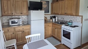 Une cuisine avec des meubles de rangement en bois, un four à micro-ondes, un réfrigérateur, une cuisinière et un évier.