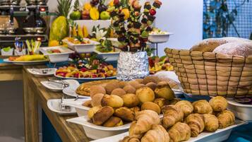 Un bufé con diversos alimentos, entre ellos frutas, verduras y pasteles.