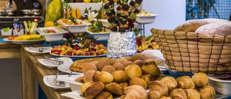 A buffet with various food items including fruits, vegetables, and pastries.