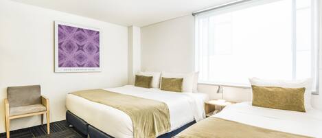 A hotel room with two beds, a chair, a nightstand, and a window.