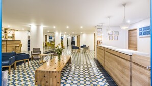 Un hall d’hôtel moderne avec un comptoir d’enregistrement, un espace salon et un sol à motifs.