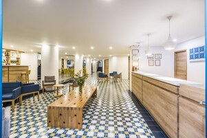 Un moderno vestíbulo de hotel con mostrador de recepción, área de estar y piso estampado.