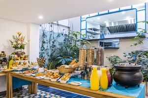 Un bufé con diversas opciones de comida, una estación de café y una barra de zumos.