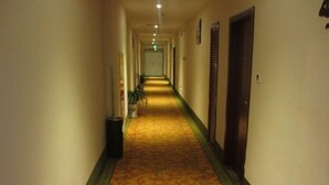 A hotel hallway with a patterned carpet, doors on both sides, and a trash bin on the left. - Greentree Inn Suzhou Shengze Business Hotel (Suzhou)