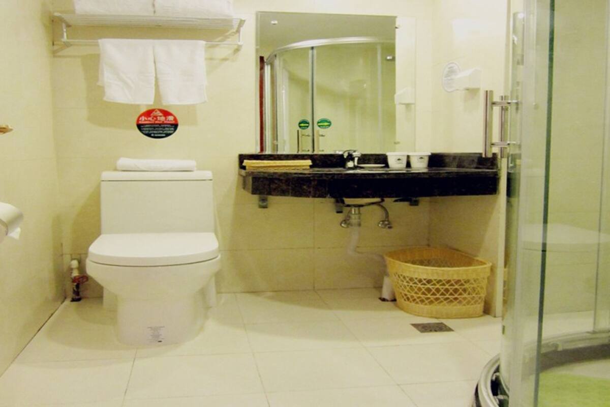 Ein Badezimmer mit Toilette, Waschbecken, einer Duschkabine aus Glas und einem Mülleimer.