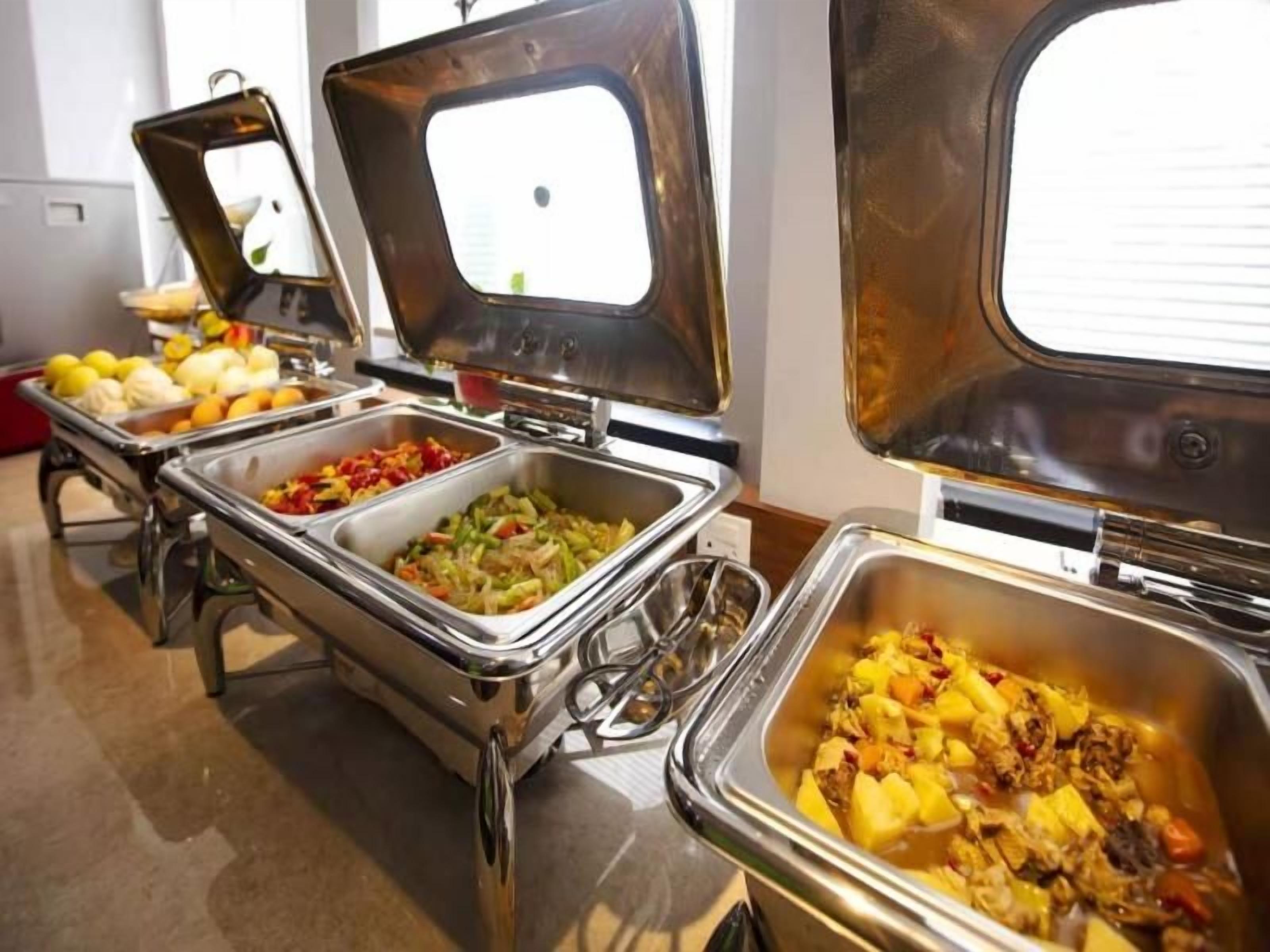 A buffet with multiple stainless steel chafing dishes containing various food items.